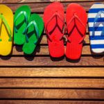 Multicolor flip-flops on wooden background. Summer family vacation concept
